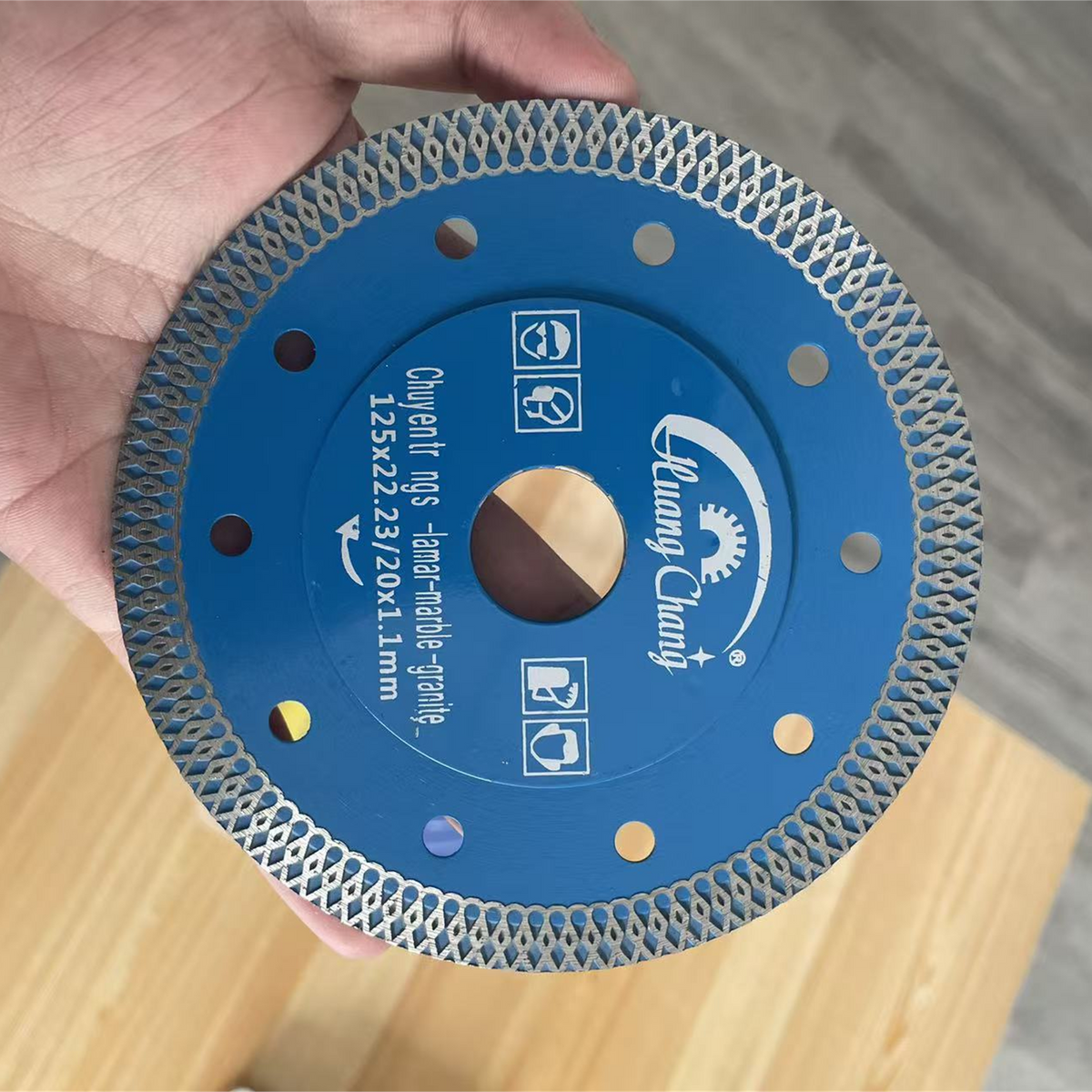 Hand holding the 125 mm Huang Chang blue diamond tile cutting blade
