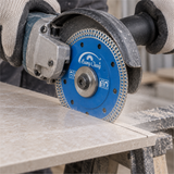 Close-up of the thin blue blade mounted with guard at a ceramic tile cut