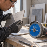 Workshop inspection of a cut ceramic tile edge with the blade nearby