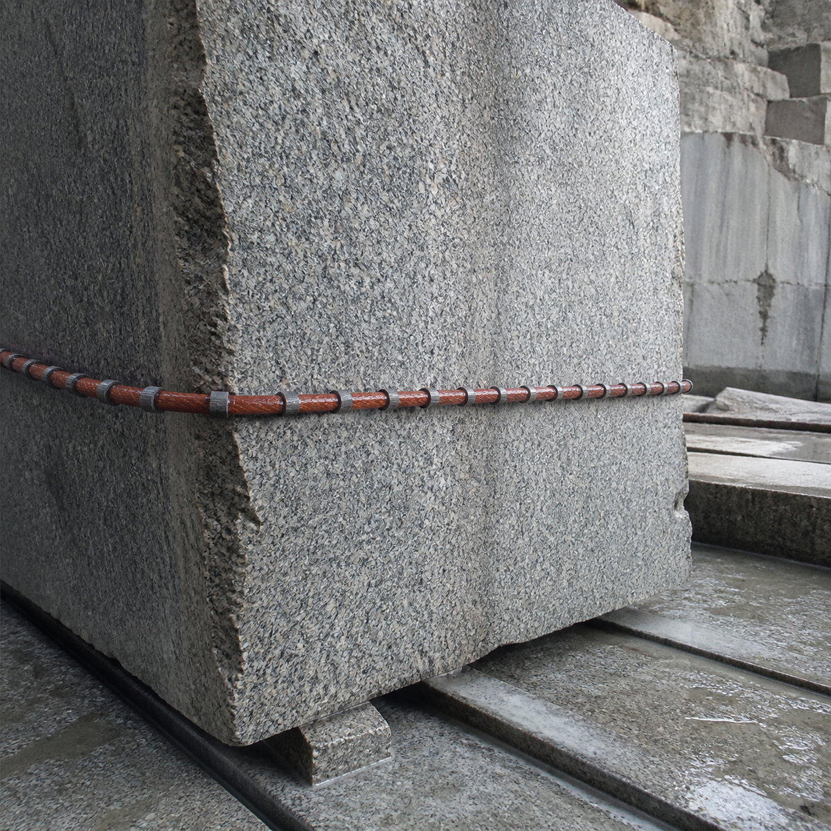 Rubber coated diamond wire saw cutting a granite quarry block